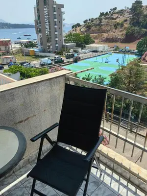 a black chair sitting on a balcony with a playground at Small duplex near beach in Sutomore