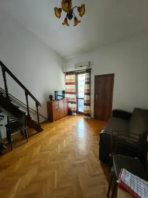 a living room with a couch and a wooden floor at Small duplex near beach in Sutomore