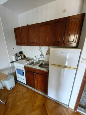 a kitchen with a white refrigerator and wooden cabinets at Small duplex near beach in Sutomore