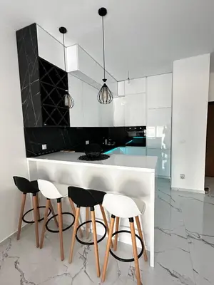 a kitchen with white cabinets and a counter with stools at Ulcinj La Miga2 in Ulcinj