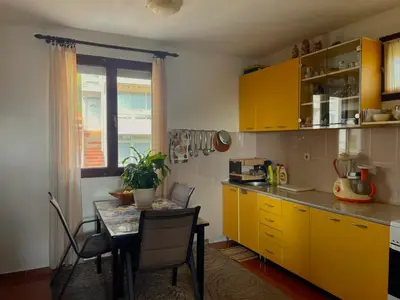 a kitchen with yellow cabinets and a table with chairs at Trosoban stan in Bar