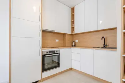 a white kitchen with white cabinets and a sink at Apartments BB in Becici