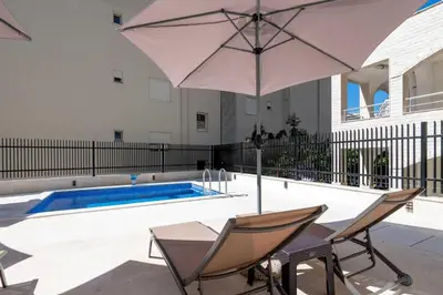an umbrella and chairs next to a swimming pool at Apartments BB in Becici