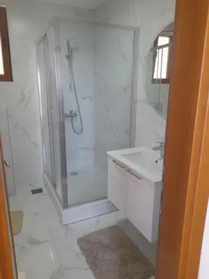 a white bathroom with a shower and a sink at Apart SASHENKA 2 in Dobra Voda