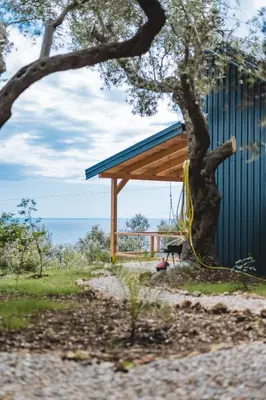 a building with a tree and a swing at Olive Hills holiday homes 3 in Dobra Voda