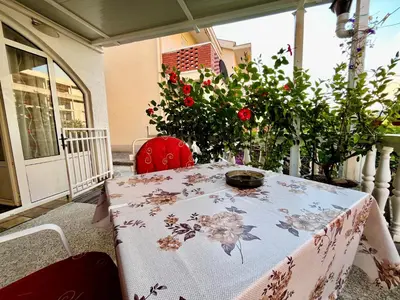 a table with a table cloth on a porch with flowers at Apartments Gvozdenović in Petrovac na Moru