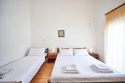 two beds in a room with white walls and a window at Family Apartments Mont Budva in Budva