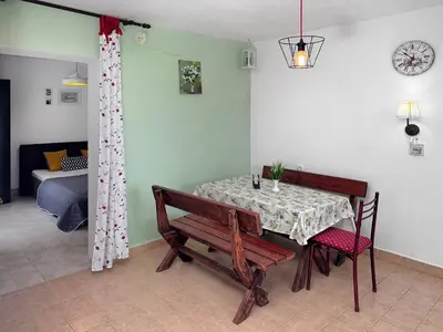 a dining room with a table and chairs and a room with a bed at Ceres Apartments in Utjeha