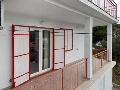 a balcony with red metal gates on a white house at Ceres Apartments in Utjeha