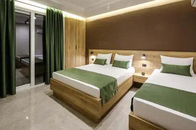 two beds in a bedroom with green curtains at Apartments Piano in Utjeha