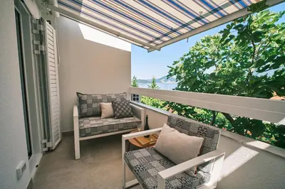 a balcony with chairs and a couch and a window at Mind Wellness Montenegro in Sveti Stefan