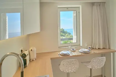 a kitchen with a table with chairs and a window at Mind Wellness Montenegro in Sveti Stefan