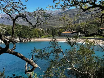 a body of water with a beach and a building at Mind Wellness Montenegro in Sveti Stefan