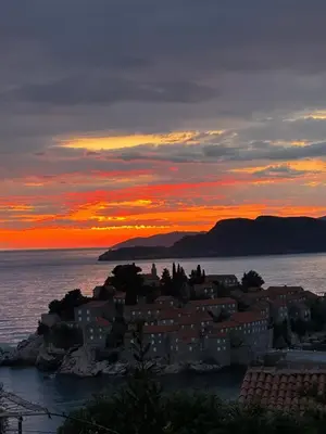 a city on the shore of the ocean at sunset at Mind Wellness Montenegro in Sveti Stefan