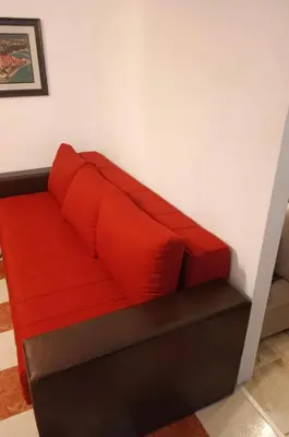 a red couch with two red pillows on it at Mia apartments in Petrovac near the sea in Petrovac na Moru