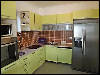 a kitchen with yellow cabinets and stainless steel appliances at Villa VIktoria in Petrovac na Moru