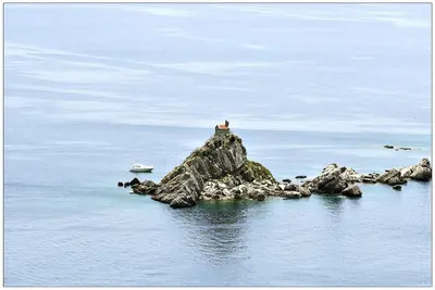 a person sitting on a rock in the water at Villa VIktoria in Petrovac na Moru