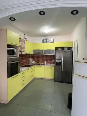 a kitchen with yellow cabinets and a stainless steel refrigerator at Villa VIktoria in Petrovac na Moru