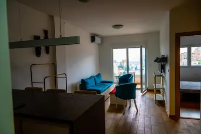 a living room with a blue couch and a bedroom at Modern City Flat Budva - Balcony & Garage Included in Budva