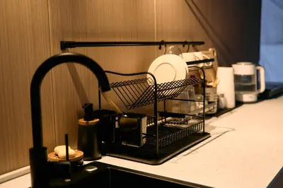a kitchen sink with a dish drying rack with dishes at GO Glamping in Dobra Voda