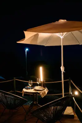 a table with a candle and an umbrella at night at GO Glamping in Dobra Voda