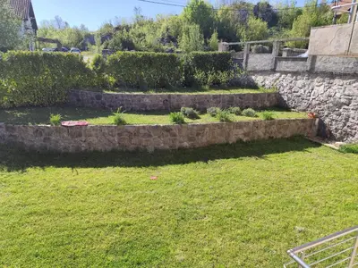 a garden with a stone wall and some grass at Kaludjerovic in Cetinje
