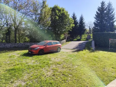 a red car parked in the grass in a yard at Kaludjerovic in Cetinje