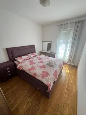 a bedroom with a bed and a desk and a window at City Apartment in Podgorica