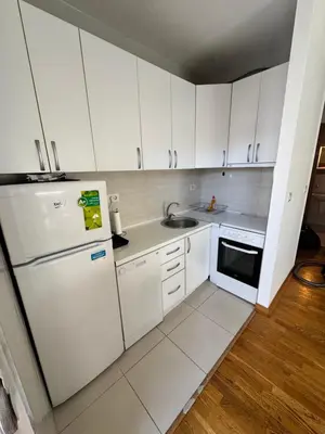 a small kitchen with white cabinets and a refrigerator at City Apartment in Podgorica