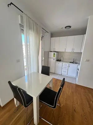 a white table and chairs in a room with a kitchen at City Apartment in Podgorica