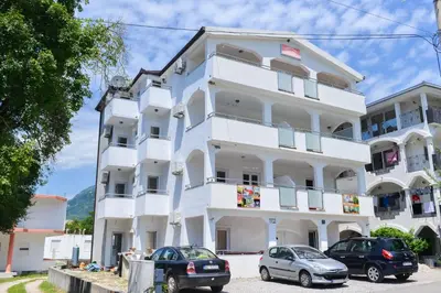 a white building with cars parked in front of it at M&D Apartments Jaz in Budva
