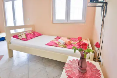a bed with a vase of flowers on a table at M&D Apartments Jaz in Budva