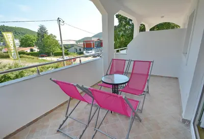 two pink chairs and a table on a balcony at M&D Apartments Jaz in Budva