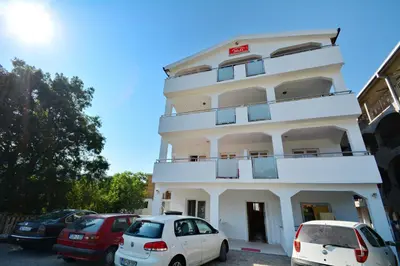 two cars parked in front of a white building at M&D Apartments Jaz in Budva