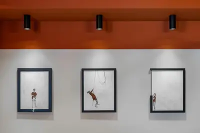 a group of framed pictures on a wall with lights at U-NIGHT Hostel Budva in Budva