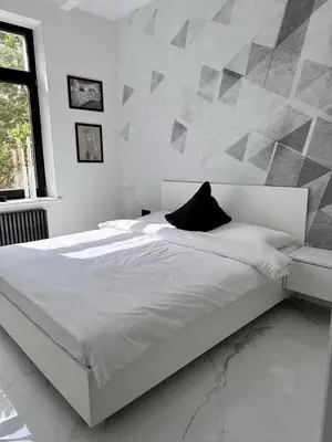 a white bed with a black pillow on it in a bedroom at Apartments Silversany in Budva