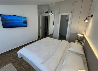 a white bed in a room with a picture on the wall at Gymnasium Rooftop Suite in Podgorica