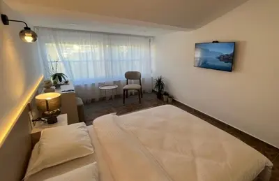 a bedroom with a bed and a table with a chair at Gymnasium Rooftop Suite in Podgorica