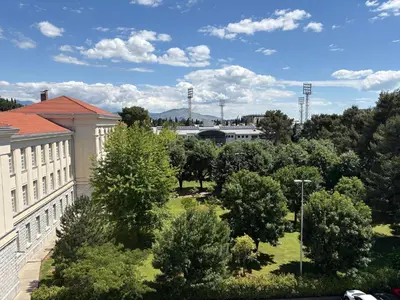 a view of a park with trees and a building at Gymnasium Rooftop Suite in Podgorica