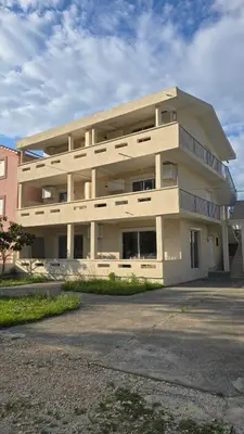 a large white building with a parking lot at SHARRI Apartments in Ulcinj