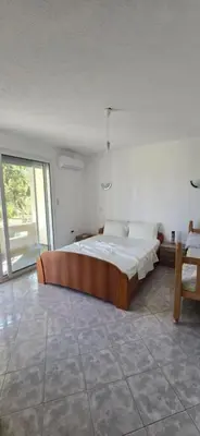 a bedroom with a large bed and a chair at SHARRI Apartments in Ulcinj