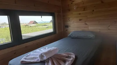 a bedroom with a bed in a wooden cabin with a window at Era Cottage in Ulcinj