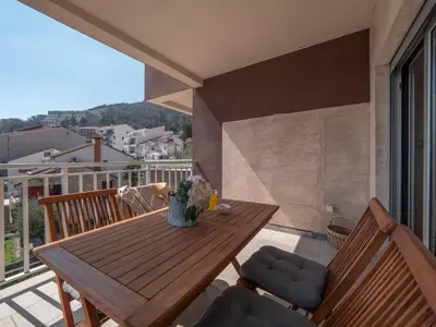a wooden table and chairs on a balcony at Tucked in 2br apt with terrace in Budva in Budva