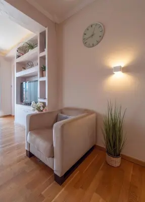 a living room with a couch and a clock on the wall at Tucked in 2br apt with terrace in Budva in Budva