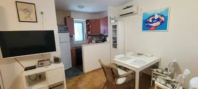 a living room with a television and a table with chairs at Аппартаменты Магнолия in Petrovac na Moru