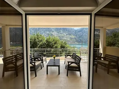 a screened porch with a table and chairs and a view at Studio apartment with heated pool in Kotor