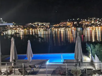 two white umbrellas sitting next to a swimming pool at night at Studio apartment with heated pool in Kotor