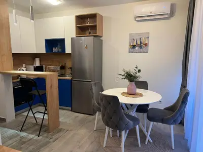 a small kitchen with a table and a refrigerator at Budva APT in Budva