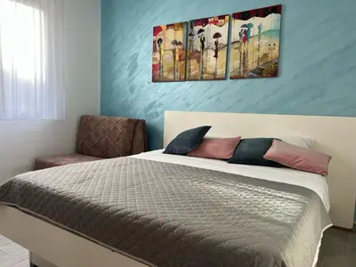 a bedroom with a bed and a painting on the wall at Budva APT in Budva