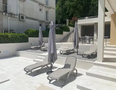 a group of chairs and umbrellas on a patio at Sea view apartment with heated pool in Kotor